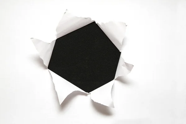 La hoja de papel con el agujero contra el fondo negro — Foto de Stock