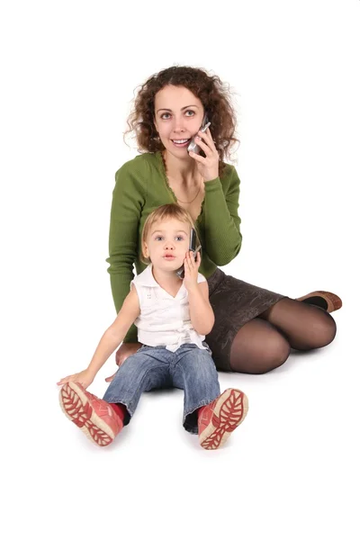 Mother and daughter sitting they talk on the cell phones on the the white 2 — Stock Photo, Image