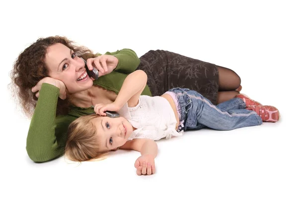Mother and daughter lie they talk on the cell phones on the the white — Stock Photo, Image