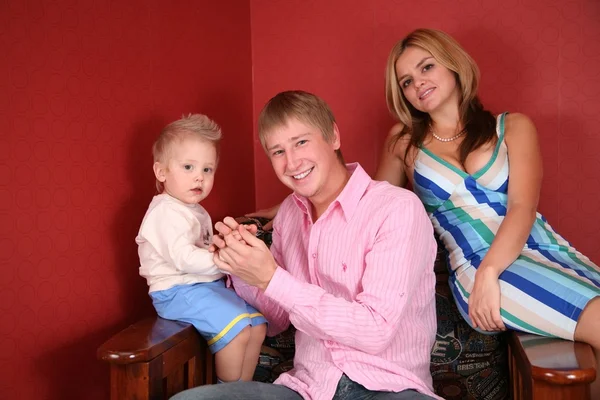 Jovem família em poltrona na sala vermelha — Fotografia de Stock