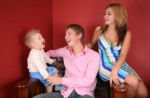 Junge Familie lacht im roten Zimmer — Stockfoto