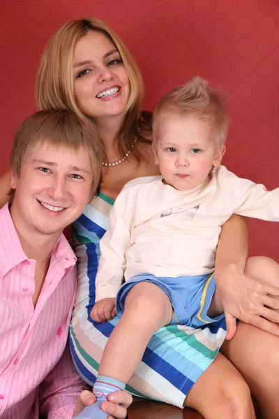Sorrindo jovem família no quarto vermelho — Fotografia de Stock