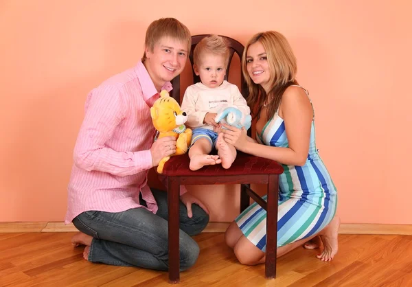 Γονείς με γιο σε καρέκλα στο ροζ δωμάτιο — Φωτογραφία Αρχείου