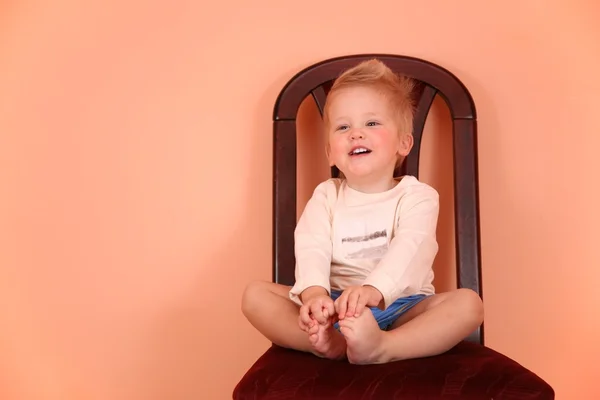 Child sit on chair in pink room — Stock Photo, Image