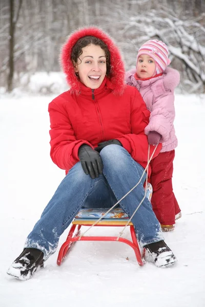 Mother sits on sled in park with child at winter — Stock Photo, Image