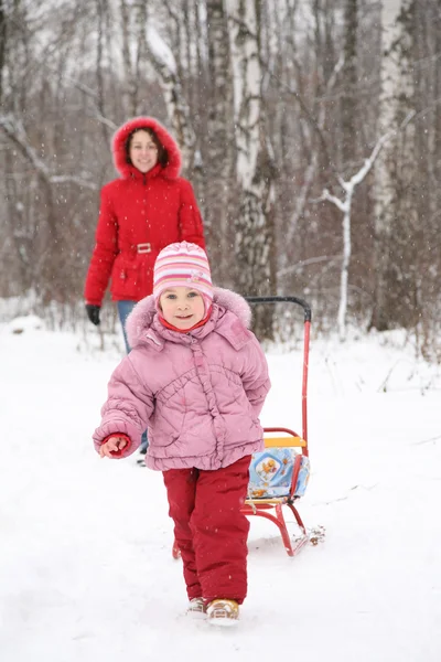 Child with sled and mother in park at winter — Stock Photo, Image