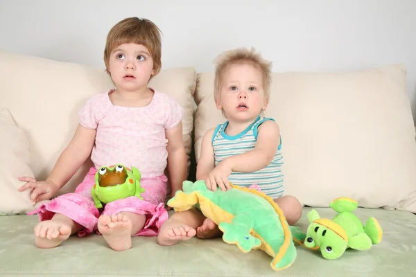 Dwoje dzieci na kanapie z zabawkami — Zdjęcie stockowe