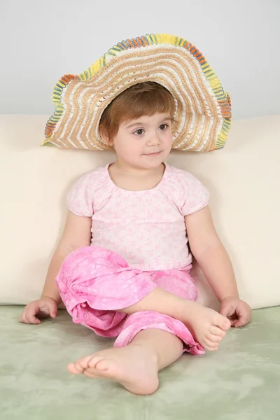 Дівчина на дивані в солом'яному капелюсі — стокове фото