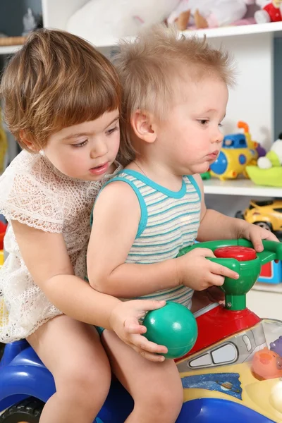 在游戏室玩具滑板车上的两个孩子 — 图库照片