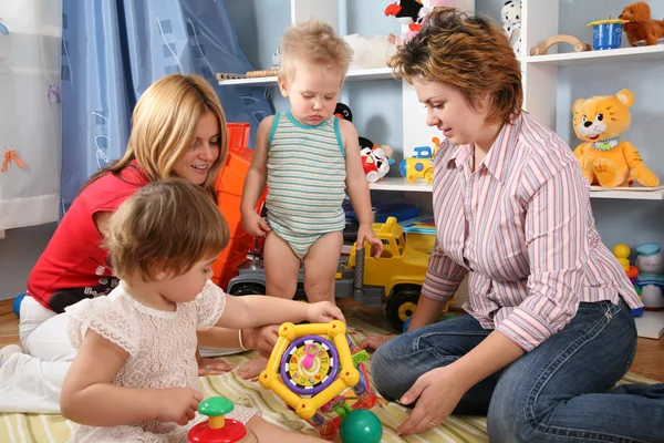 Две матери с детьми в игровой комнате — стоковое фото