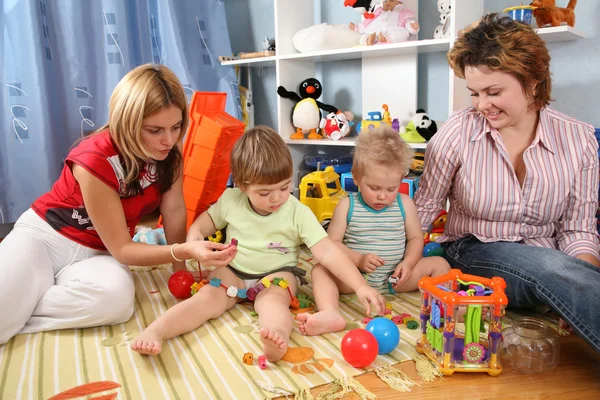 Two mothers play with children in playroom — Stock Photo, Image