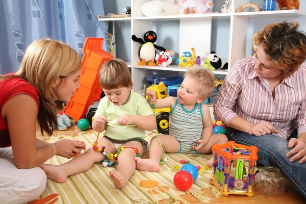 Two mothers play with children in playroom 2 — Stock Photo, Image