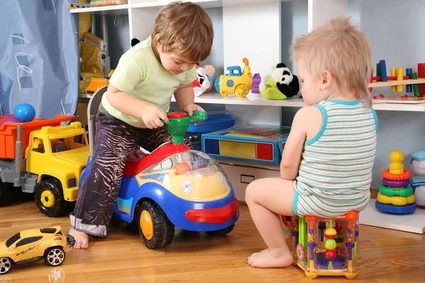 Двое детей в игровой комнате с игрушечным скутером — стоковое фото