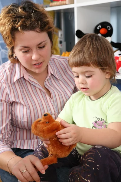 Мать с ребенком в игровой комнате с мягкой игрушкой — стоковое фото
