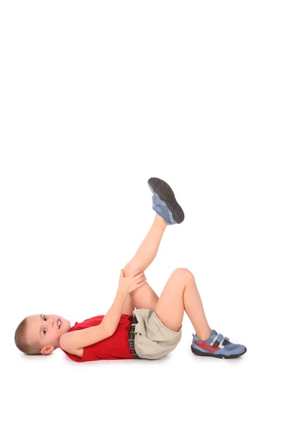 Хлопчик лежить з ногою вгору на білому — стокове фото
