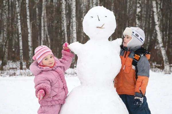 Αγόρι και κορίτσι κάνει χιονάνθρωπο — Φωτογραφία Αρχείου