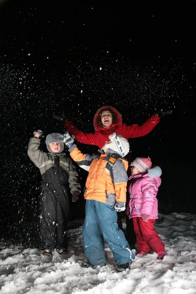 Kinderen en moeder gooien sneeuw in de nacht — Stockfoto