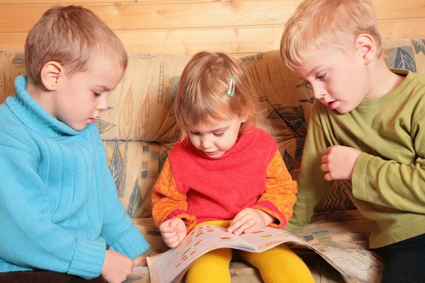 Děti číst knihu na pohovce v dřevěné místnosti 2 — Stock fotografie