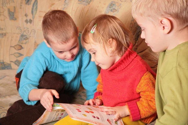 Niños leer libro en el sofá en la habitación de madera 4 —  Fotos de Stock