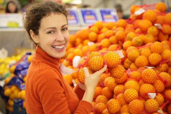 Jeune femme avec des oranges en magasin — Photo