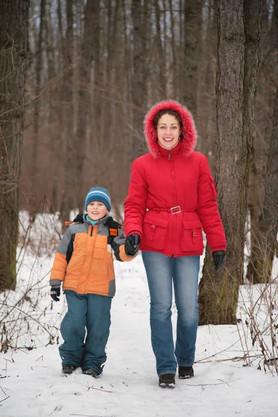 Мать с сыном гуляют в лесу зимой — стоковое фото