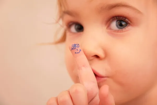 Liten flicka och finger med målat ansikte — Stockfoto