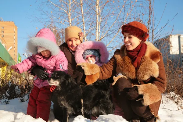 Two mothers with children and dog on street in winter — Stock Photo, Image