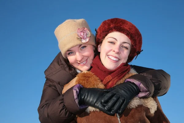 Jonge vrouw omvat andere tegen blauwe hemel in de winter — Stockfoto