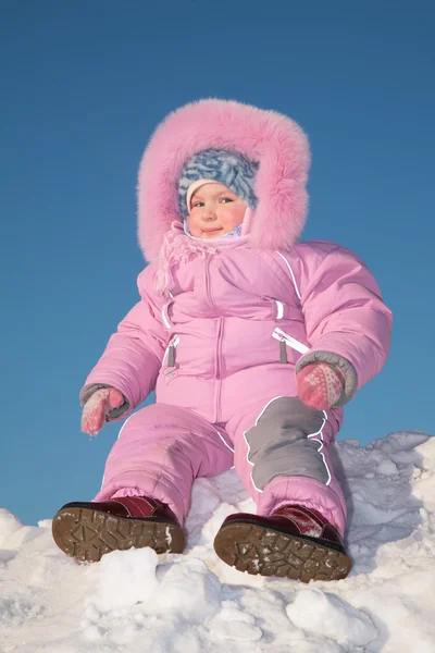 Ребенок сидит на снежном холме — стоковое фото