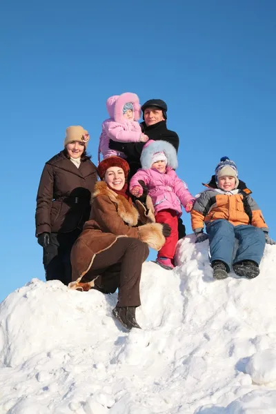 Две матери с дедушкой и детьми на снежном холме — стоковое фото