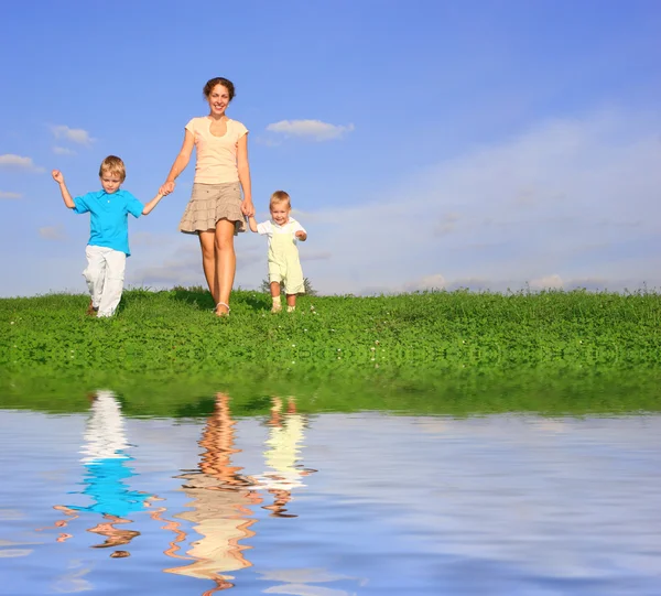 Mãe com crianças em prado e água — Fotografia de Stock
