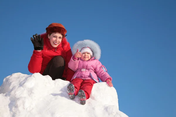 Mother with child sit on snow hill — Stock Photo, Image