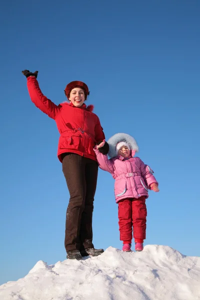 Мать и ребенок стоят на вершине снежного холма — стоковое фото