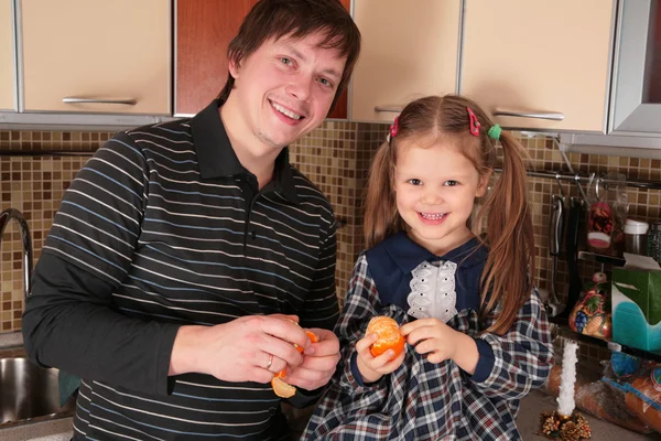 Отец и дочь с мандаринами на кухне — стоковое фото