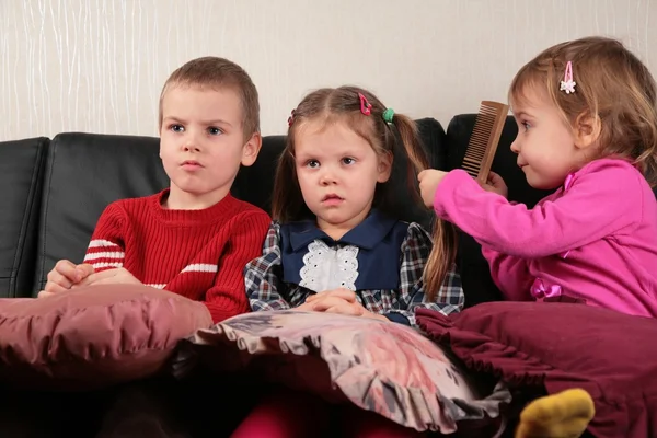 Трое детей на диване смотрят телевизор — стоковое фото