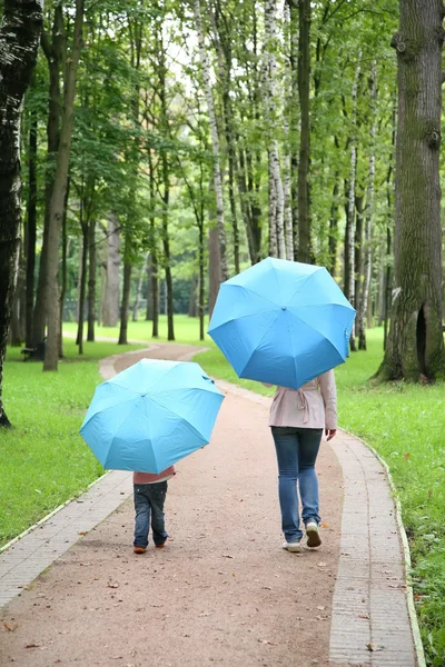 Mother with the child under the umbrellas in the park Stock Photo