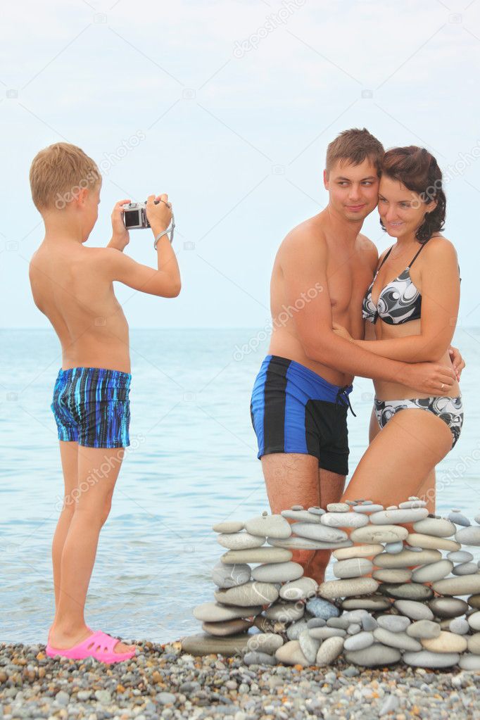 Boy with photocamera is making photo of his parents