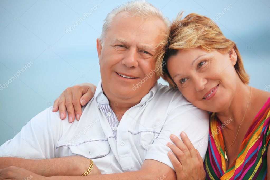 Smiling elderly married couple on veranda near seacoast, concern