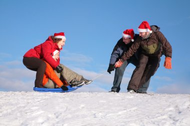 Two men pull two women on sled clipart