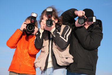 Three photographers against blue sky clipart