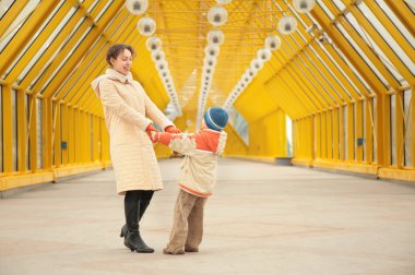 Mother and son hold each other for hands on footbridge clipart