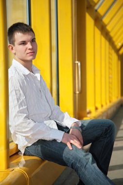 Young man sits on footbridge clipart