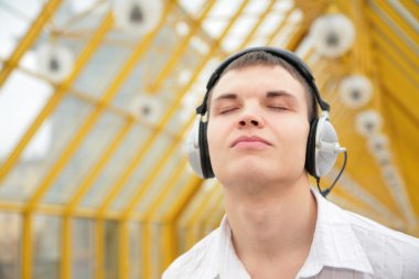 Young man listens music on footbridge clipart