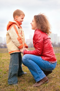 Mother and son look on each other outdoor on spring clipart