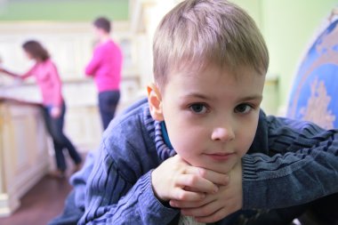 Portrait of pensive boy on kitchen against background of parents clipart