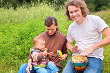 Parents and baby on nature with musical instruments clipart