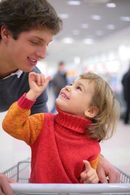 Father with child in cart in shop clipart