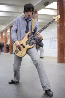 Young musician play on guitar at metro station clipart