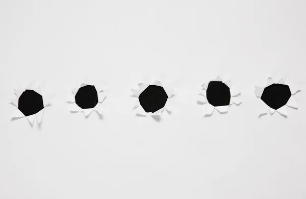 Sheet of paper with row of holes against black background — Stock Photo, Image