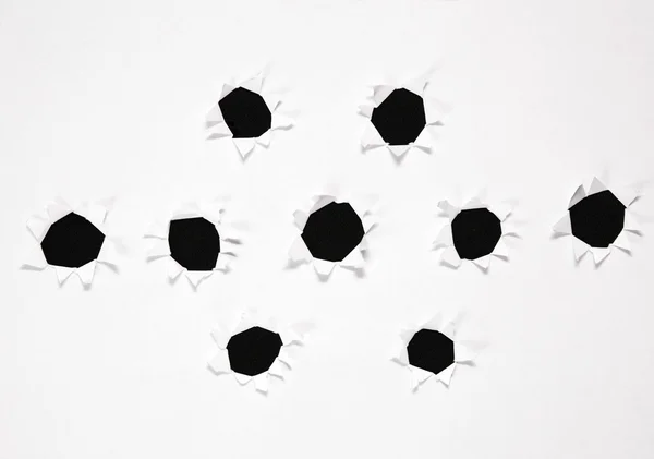 A folha de papel com o grupo de furos contra o fundo preto — Fotografia de Stock
